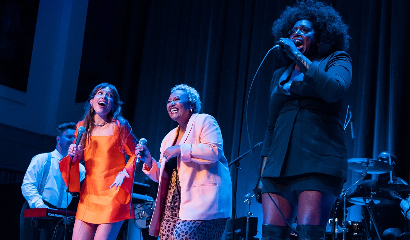 Diverse people singing on stage with colourful clothes