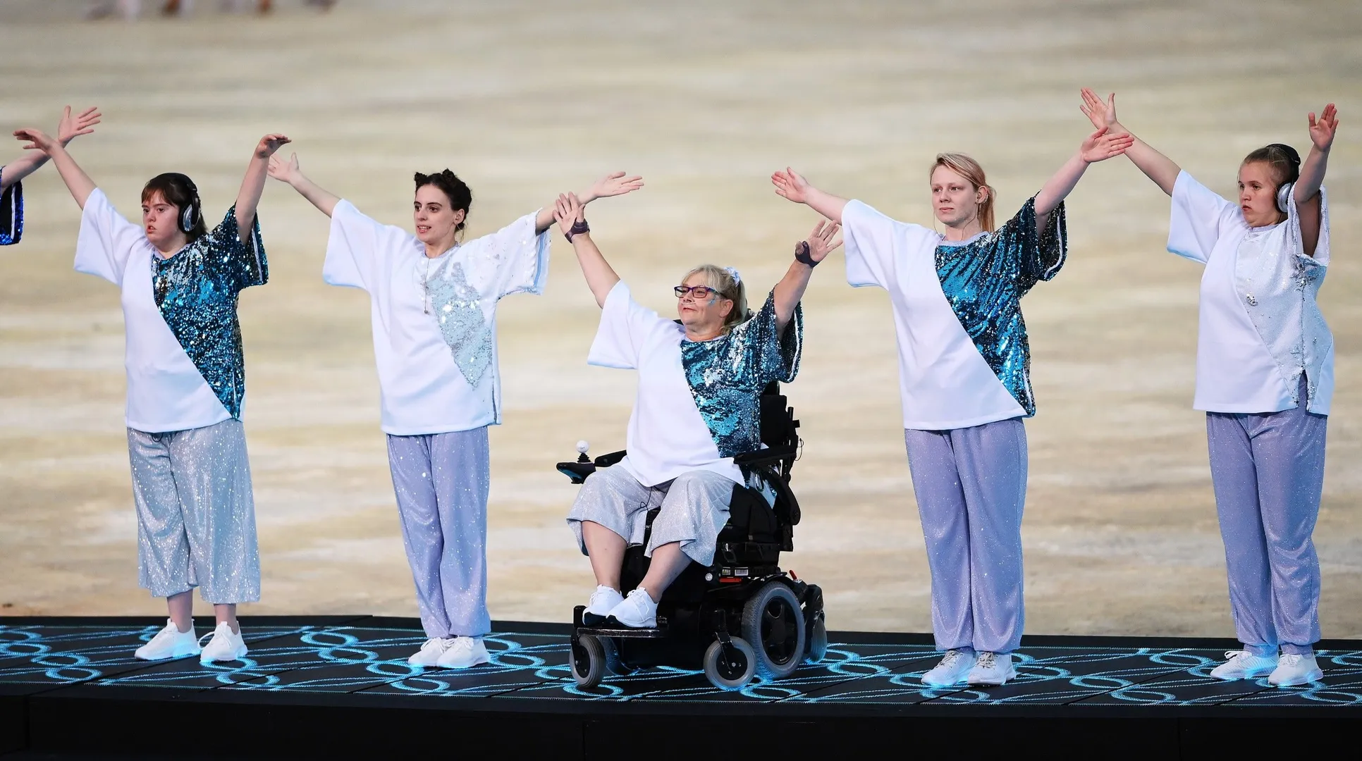 Dancers on a stage, including one wheelchair user and some with ear-protection